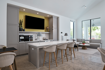 a kitchen and living room with a large white island with stools and a yellow accent wall at Odyssey, Florida, 33905